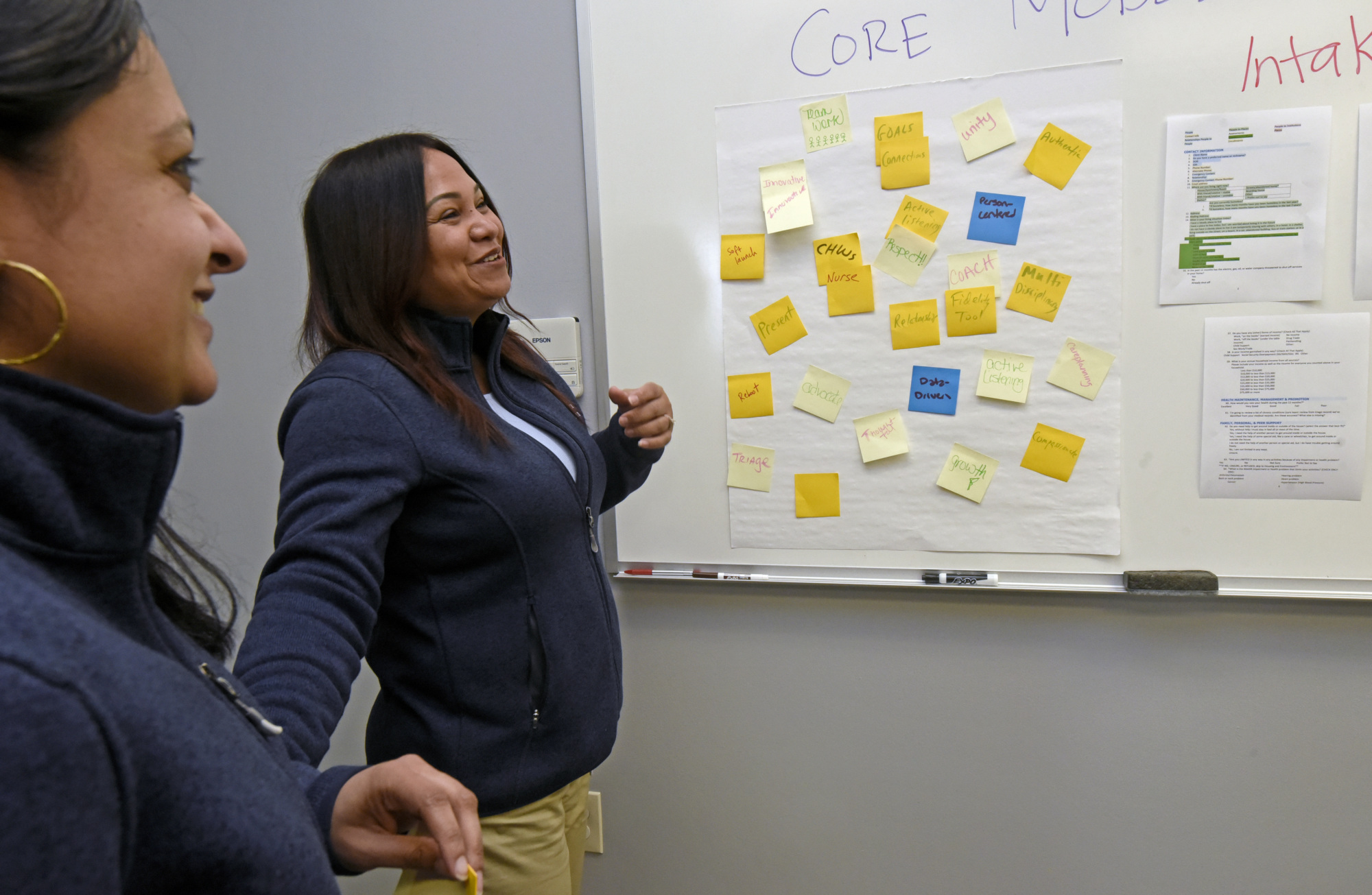 Camden Coalition staff laugh in front of white board covered with post-its