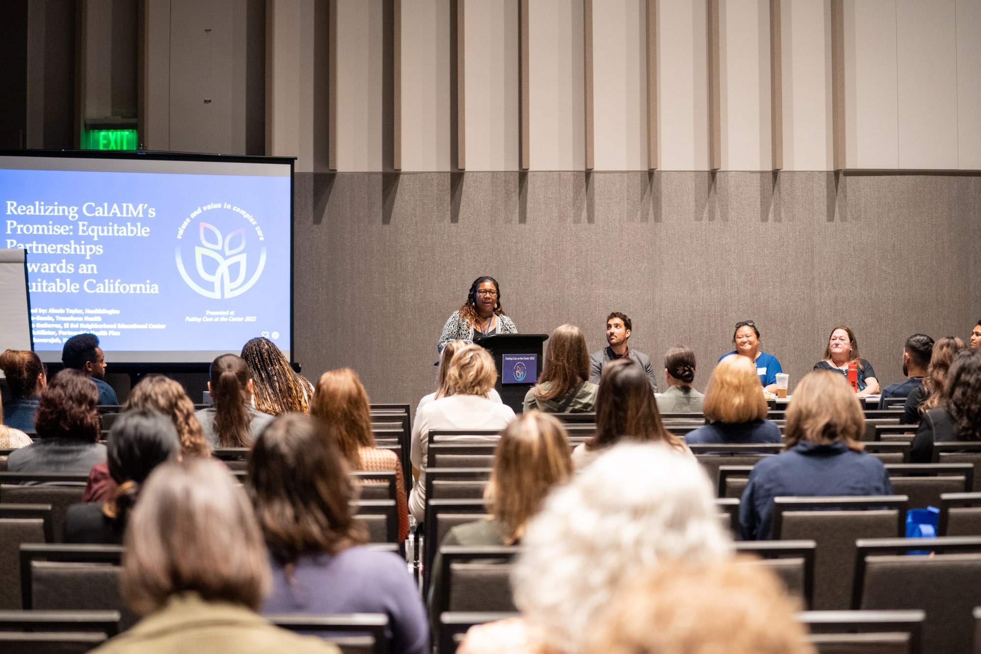 A speaker presents about CalAIM at a Putting Care at the Center conference