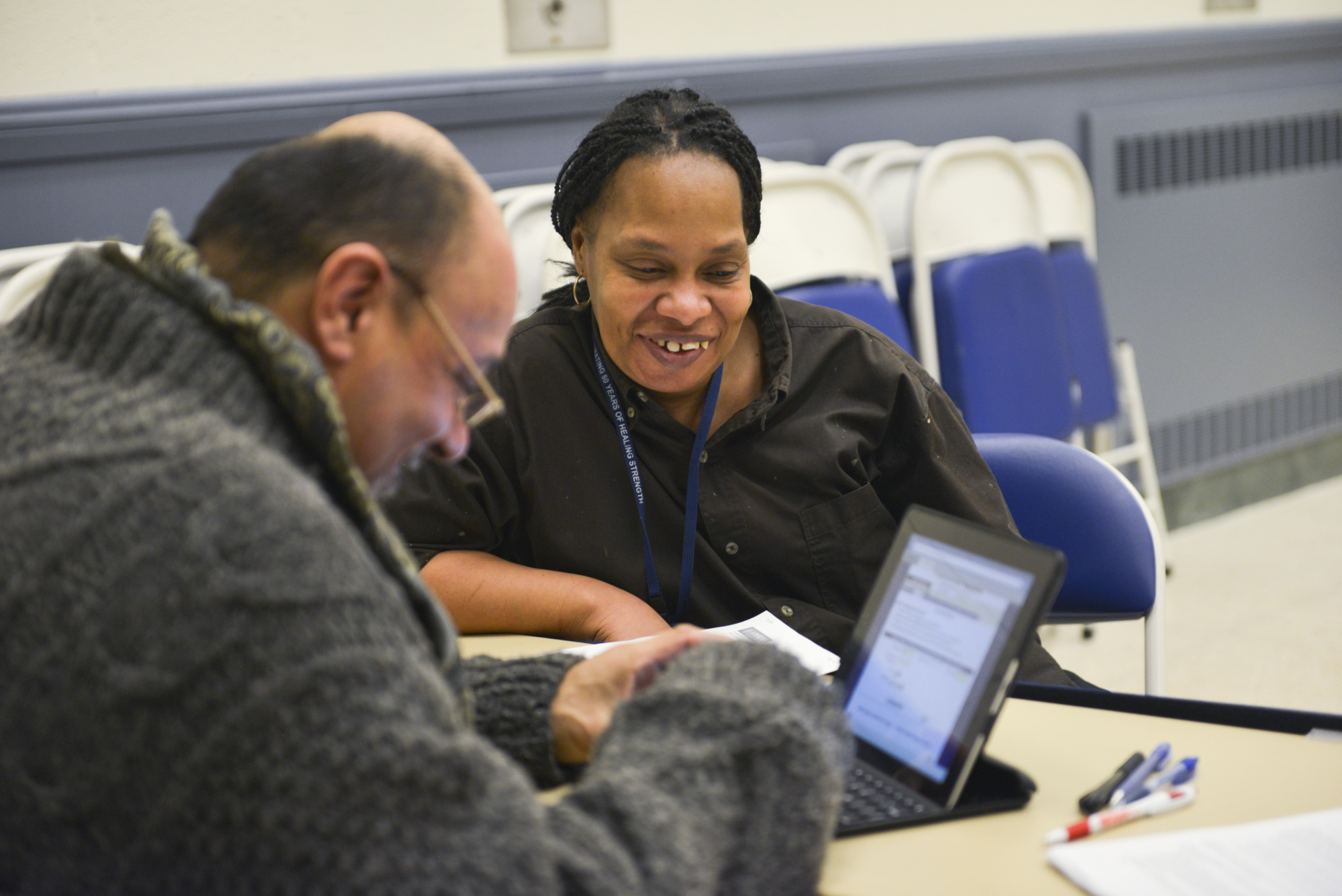 A man and woman look at a computer at a community health event
