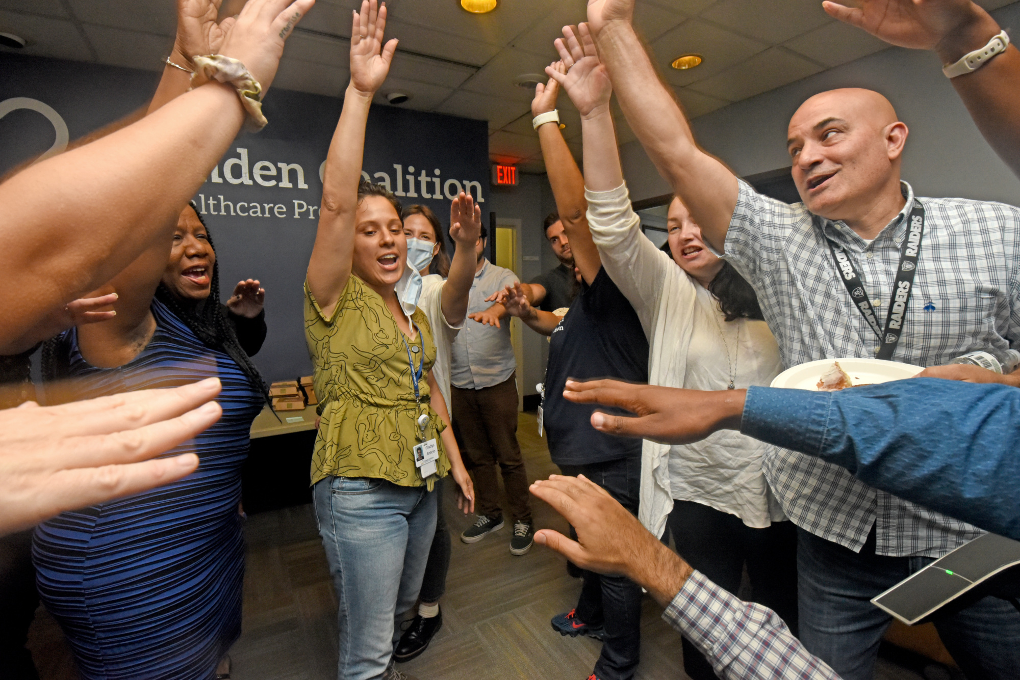 Camden Coalition staff lift their hands in unison to end a team huddle
