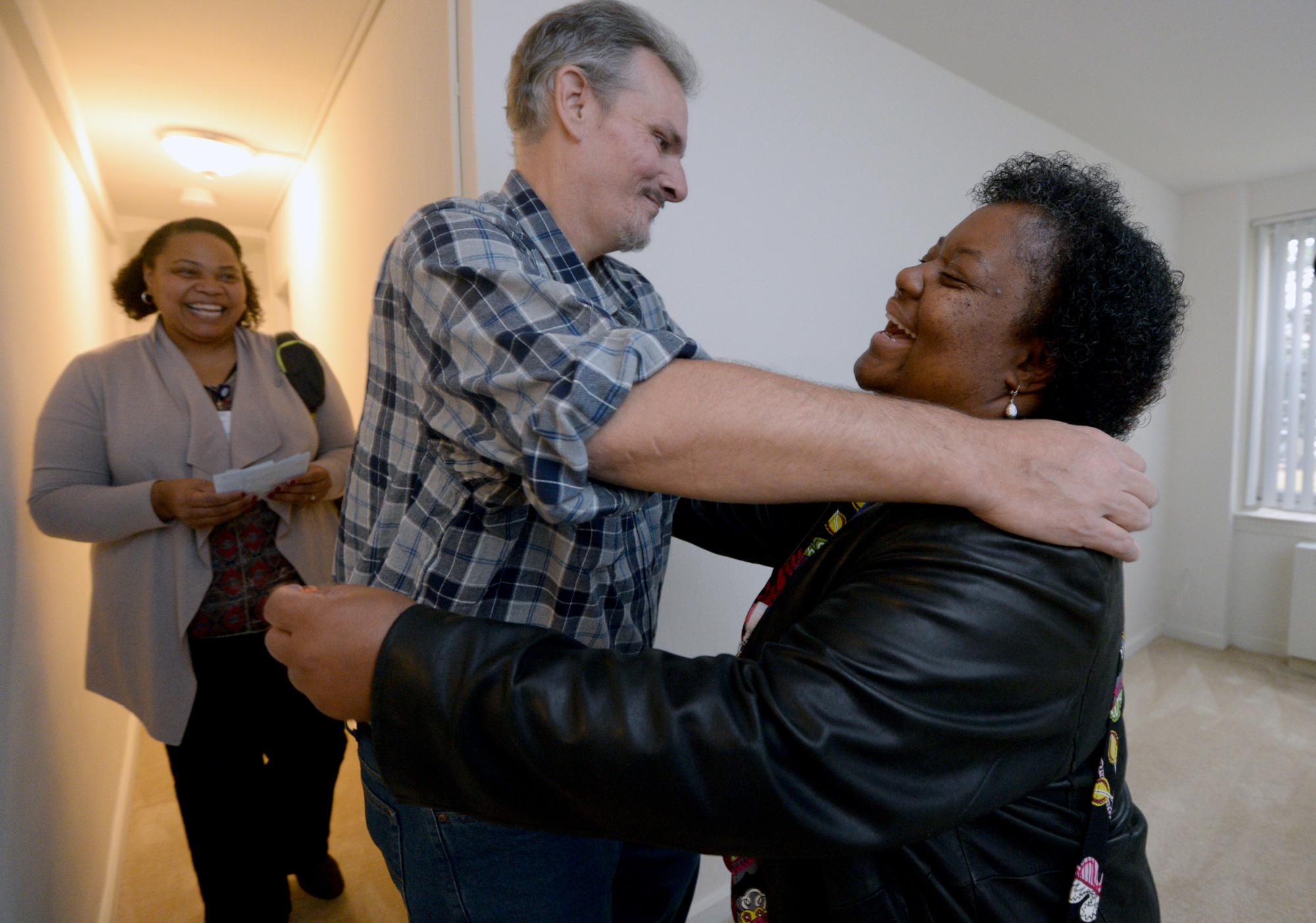 Housing First participant hugs community health worker in his new apartment