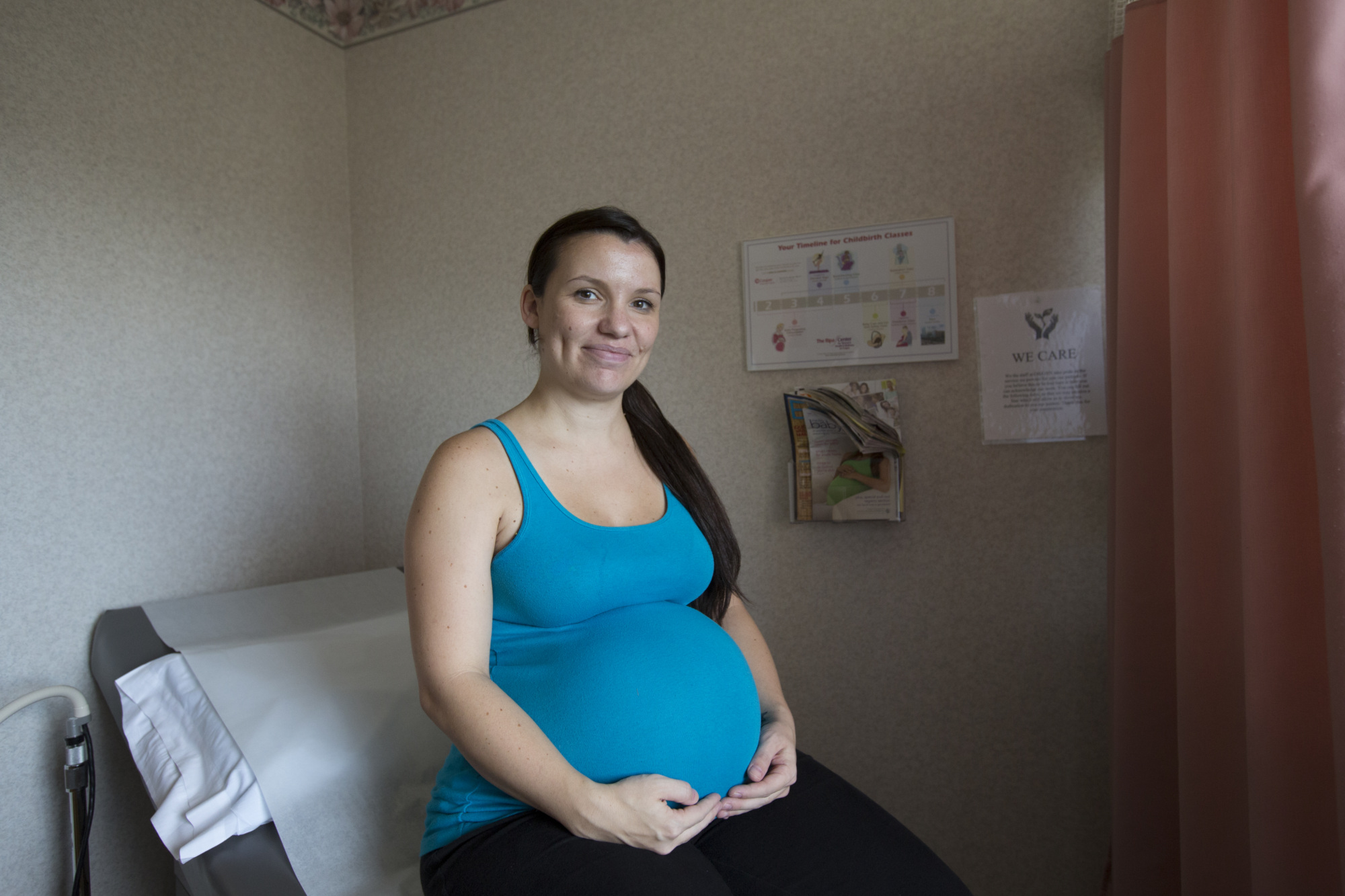 A pregnant patient sits on an exam table