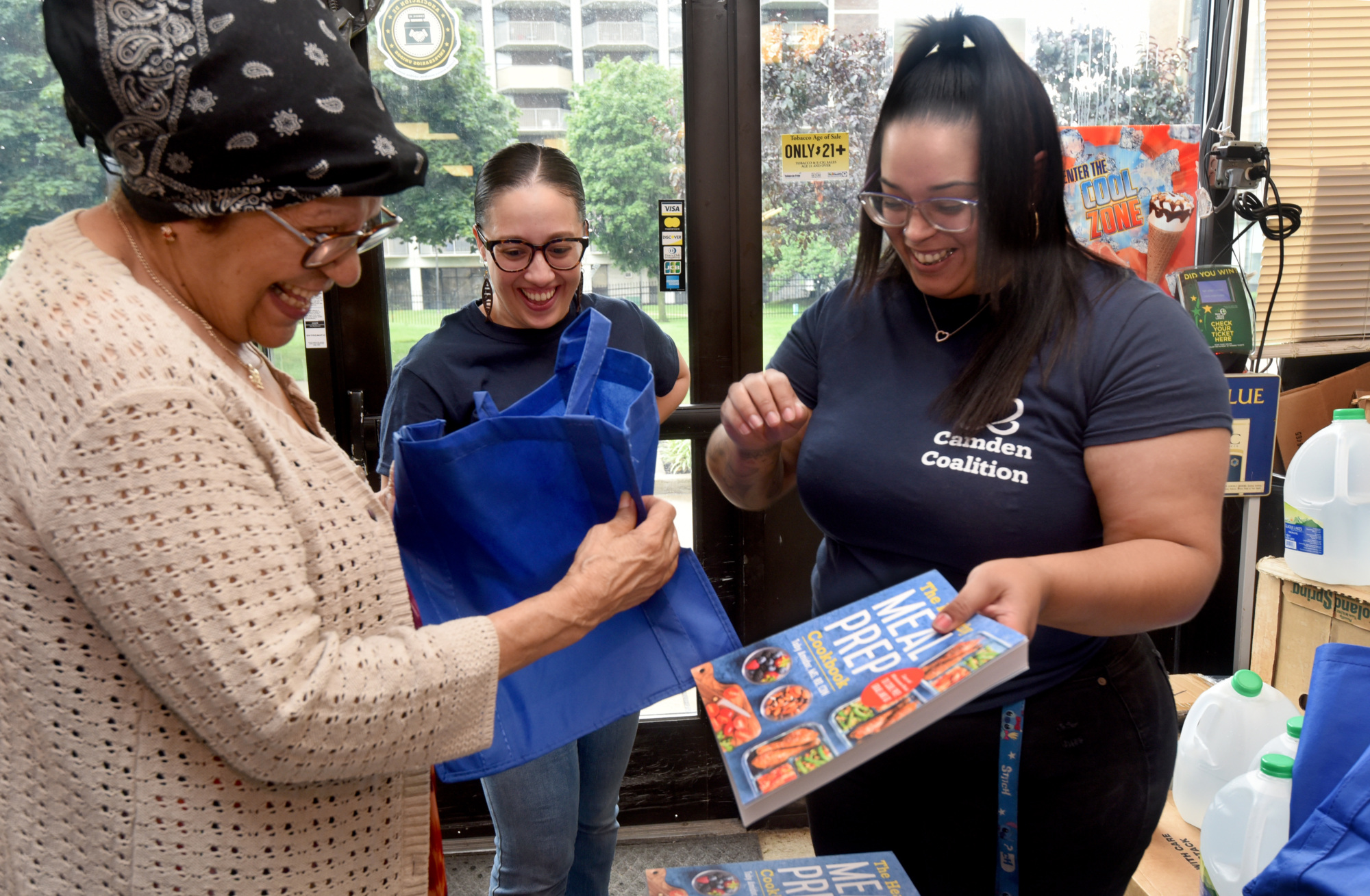 Camden Coalition CHWs hand a cookbook to a community member